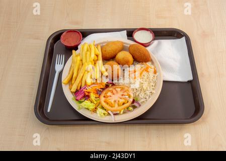Kombinierter Teller mit Kroketten, gekochtem weißem Reis, Salat mit Salat und Tomaten und Pommes Frites mit Saucen Stockfoto