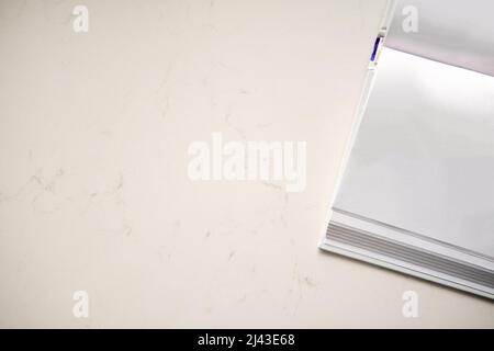 Offenes Hardcover-Buch mit leeren weißen Seiten liegt auf einem Kunststeintisch. Kopierbereich Hintergrund, Draufsicht flach Lay Overhead Stockfoto