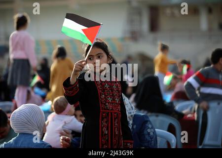 Gaza, Palästina. 11. April 2022. Ein palästinensisches Kind sah während einer Party für Waisenkinder in Gaza-Stadt, anlässlich des „Arabischen Waisenkindes-Tages“, die palästinensische Flagge tragen. Kredit: SOPA Images Limited/Alamy Live Nachrichten Stockfoto