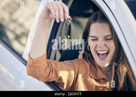 Fahren Sie langsam und genießen Sie die Landschaft. Aufnahme einer Frau, die die Schlüssel zu ihrem neuen Auto vor der Tür hält. Stockfoto