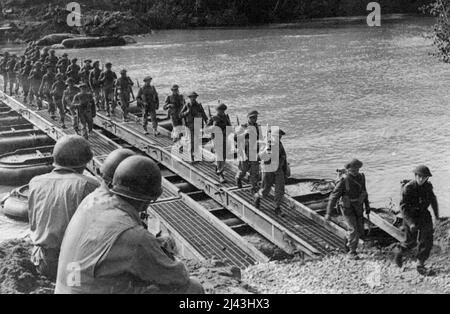 Über den Fluss Volturno: Drei amerikanische Ingenieure beobachten britische Truppen und den Transport über die Volturno-Brücke. Am 13.. Oktober 1943, unter dem Deckmantel der Dunkelheit hat die Fünfte Armee ihren großen Angriff auf den Fluss Volturno, eine der größten Barrieren, um nach Rom vorzudringen - und ist in Kraft getreten. 31. Oktober 1943. (Foto von Fox Photos). Stockfoto