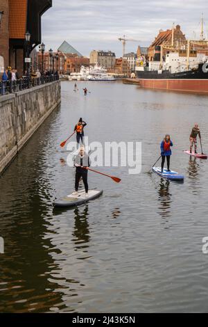 Danzig Polen März 2022 Gruppe von Sup-Surfern stehen auf Paddle-Board, Frauen stehen auf Paddeln zusammen in der Stadt Motlawa Fluss und Kanal in der Altstadt Danzig Polen. Tourismusattraktion Aktive Erholung im Freien Soziale Distanzierung Reiseziele Stockfoto