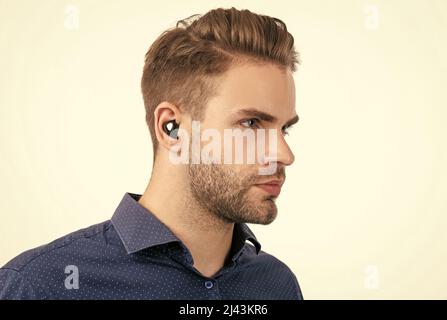 Schöner, unrasierter Mann mit kabellosen bluetooth-Ohrhörern, die auf weißer Bluetooth-Technologie isoliert sind Stockfoto