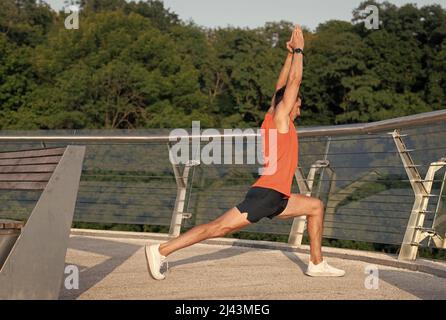 Fit Mann halten virabhadrasana Pose tun Halbmond Ausfallschritt Strecke auf Promenade, Yoga Stockfoto