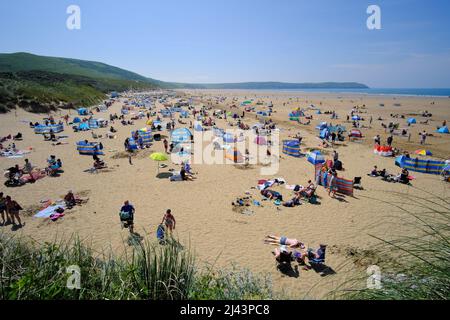 Die Menschen genießen die Sonne an einem Sandstrand im Badeort Woolacombe an der Küste von North Devon England Stockfoto
