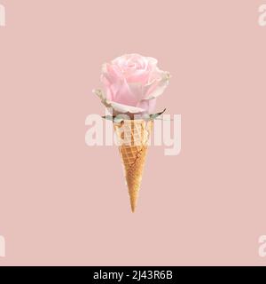 Zartrosa Rosenblüte in einem Eiswaffel-Kegel, Sommerfrühlingslicht-Konzept, Postkarte, Muster, pulverförmiger Hintergrund, Minimalismus. Stockfoto