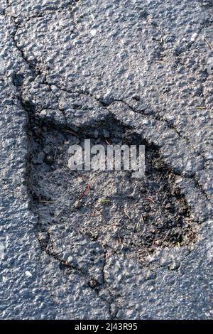 Topfloch in Asphaltstraße. Beschädigte Autobahn mit Loch darin. Gefährliche Löcher nach dem Winter repariert werden. Stockfoto