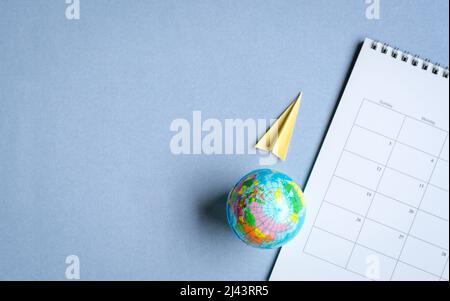 Globus mit Papierfläche und Kalender. Reisekonzept. Draufsicht mit Kopierbereich. Stockfoto