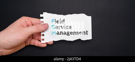 Akronym FSM oder Field Service Management. Person, die ein Stück Papier mit Text hält. Stockfoto