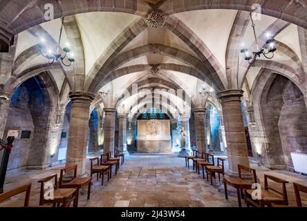 Unter der Kathedralkirche der anglikanischen Diözese Hereford. Wunderschön beleuchtete alte Bögen und niedrige Decken, Steingefliester Boden, Stühle arran Stockfoto