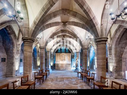 Unter der Kathedralkirche der anglikanischen Diözese Hereford. Wunderschön beleuchtete alte Bögen und niedrige Decken, Steingefliester Boden, Stühle arran Stockfoto