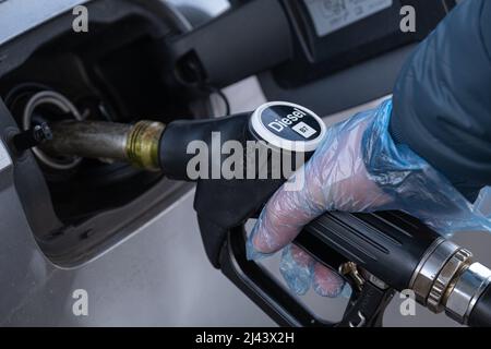 Diesel. Tanken des Autos.Füllen der Pistole in den Händen eines Mannes in einem Handschuh.Ein Mann füllt einen Tank mit Dieselkraftstoff. Kraftstoffpreis in Europa. Stockfoto