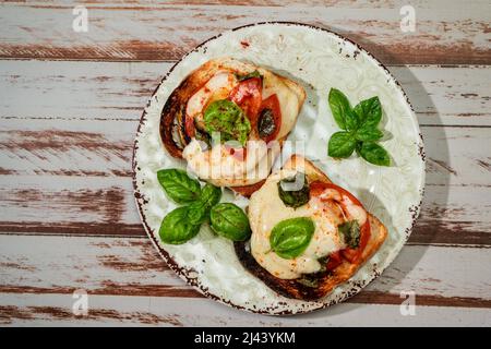 Draufsicht auf eine Brusqueta mit Mozzarella Caprese, Tomate und heißem Basilikum. Stockfoto