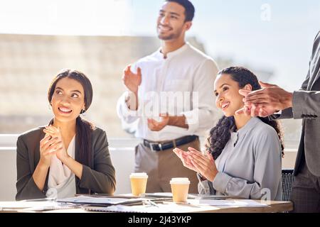 Inspiriert und begeistert, gemeinsam erfolgreich zu sein. Aufnahme einer Gruppe von Geschäftsleuten, die während einer Besprechung in einem Büro applaudieren. Stockfoto