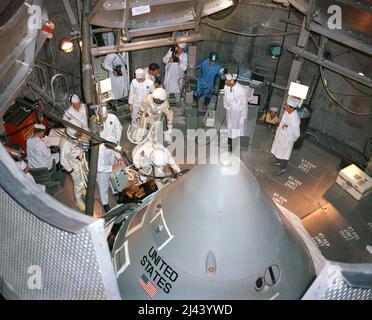 Die Apollo 1-Besatzungsmitglieder der ersten bemannten Apollo-Mission bereiten sich darauf vor, ihre Raumsonde in die Höhenkammer des Kennedy Space Center (KSC) zu betreten. Beim Betreten der Luke ist Astronaut Virgil (Gus) Grissom, Kommandopilot; hinter ihm ist Astronaut Roger Chaffee, Pilot; links mit Kammertechnikern steht Astronaut Edward White, leitender Pilot. Sie wurden alle einige Monate später bei dem Brand getötet. Stockfoto