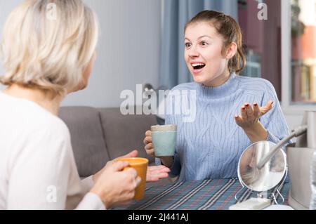 Reife Mutter spricht mit Erwachsene Tochter am Tisch. Stockfoto