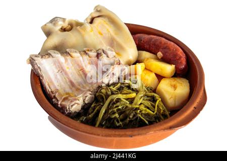 Zutaten für das galizische Eintopf-Rezept, bestehend aus Kartoffeln, Rippen, Schweineschulter, geräuchertem Ohr, Chorizo ​​​​and Rübengemüse in einer Tonschale auf einem weißen Stockfoto