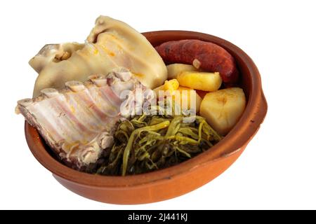 Zutaten für das galizische Eintopf-Rezept, bestehend aus Kartoffeln, Rippen, Schweineschulter, geräuchertem Ohr, Chorizo ​​​​and Rübengemüse in einer Tonschale auf einem weißen Stockfoto