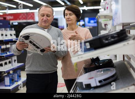 Europäische Ehegatten im reifen Alter entscheiden sich für einen Roboter-Staubsauger Stockfoto