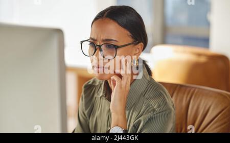 Ich habe keine Ahnung, was das bedeutet Aufnahme einer jungen Geschäftsfrau, die beim Arbeiten am Computer in einem Büro verwirrt aussieht. Stockfoto