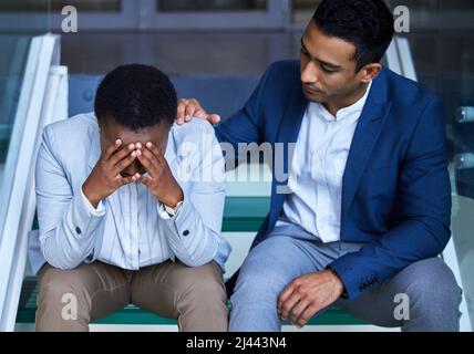 Sei stark, wenn alles schief zu laufen scheint. Aufnahme eines jungen Mannes, der seinen Kollegen bei der Arbeit tröstet. Stockfoto
