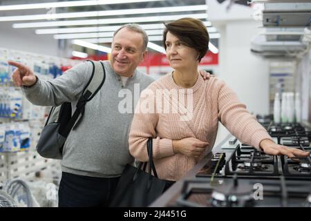 Frau und Mann mittleren Alters pflücken einen neuen Gasherd im Laden Stockfoto
