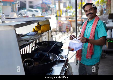 Happy Street Food Vendor verpackt Lebensmittel in Paket Stockfoto