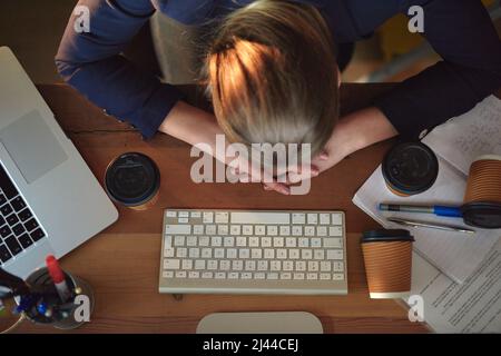 Ist es Zeit, nach Hause zu gehen? Aufnahme einer müden jungen Designerin, die auf ihrem Schreibtisch nappt und spät im Büro arbeitet. Stockfoto