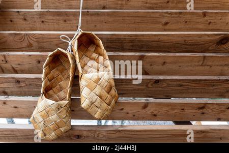 Birchen gewebte Bast-Schuhe hängen an einer Blockwand. Hochwertige Fotos Stockfoto