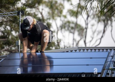 Mann installiert Solar-PV-Dachpanel auf dem Dach eines Hauses in Sydney, NSW, Australien Stockfoto