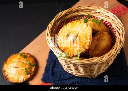 Food-Konzept hausgemachte rustikale Boden Beef Pot Hand Pie in Brotkorb auf Holzbrett mit Kopierplatz Stockfoto