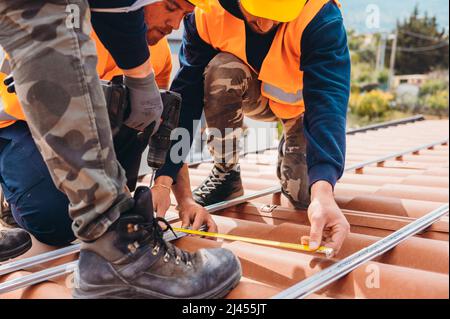 Ein Team von Technikern arbeitet auf dem Dach eines Hauses Stockfoto