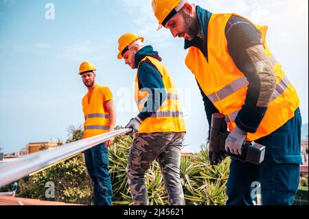 Ein Team von Technikern arbeitet auf dem Dach eines Hauses Stockfoto