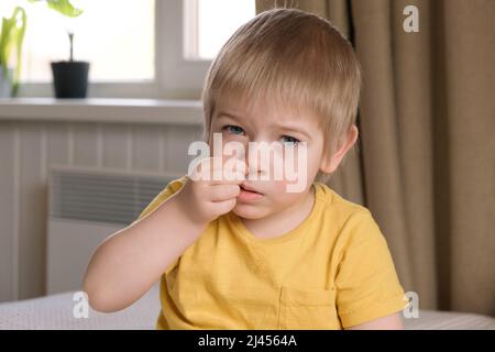 Kind Junge mit blonden Haaren Baby mit Finger in der Nase. Portrait 3 Jahre altes Kind pflückt Nase. Entwicklung der Bildung von Kindern im frühen Alter. Authentisch Stockfoto