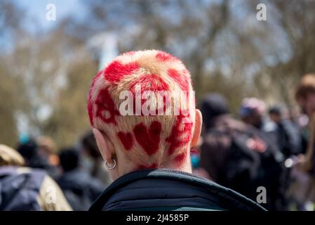 Hinterkopf einer jungen Frau mit gebleichtem Haar und roten Herzen und Anarchesymbolen, bei einem Extinction Rebellion Protest, London, England, Großbritannien Stockfoto