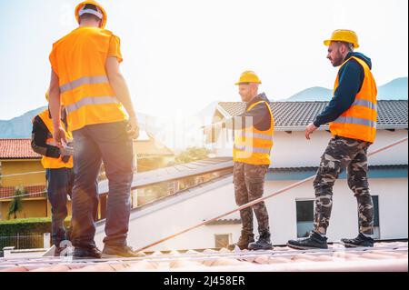 Ein Team von Technikern arbeitet auf dem Dach eines Hauses Stockfoto