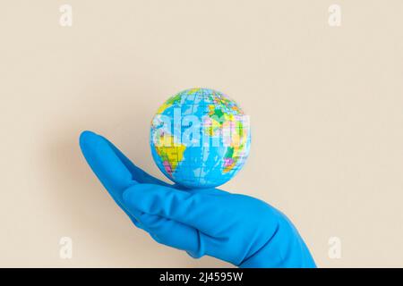 Erdkugel in Händen in blauem Schutzhandschuh auf einem sauberen. Das Konzept des Schutzes von Natur, Ökologie und globalem Frieden. COVID-19 Pandemie Stockfoto