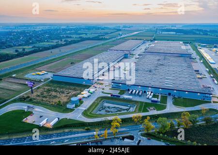 Ein erstaunlicher Blick auf den Sonnenuntergang über dem großen Lagerhaus eines großen Logistikunternehmens. Stockfoto