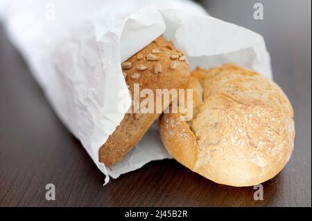 Frische knusprige Brötchen in Papiertüte auf braunem Tisch Stockfoto