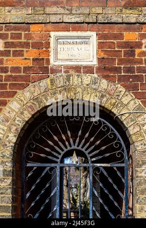 Detail eines eisernen Tores zu einer Passage durch die Benslow Terrace, die im 19.. Jahrhundert in der Benslow Lane, Hirchin, Hertfordshire, Großbritannien, erbaut wurde Stockfoto