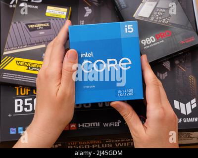Tambow, Russische Föderation - 07. April 2022 Eine Frau hält eine Box mit einer Intel Core i5 11400 CPU über andere Boxen mit brandneuen Komponenten in Stockfoto