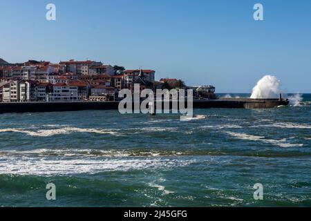 Wellen schlagen an einem sonnigen Tag gegen den Hafen von lekeitio in der kantabrischen See Stockfoto