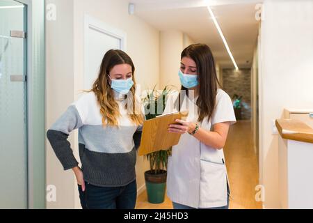 Rezeptionistin gibt Hinweise und hilft jemandem bei der Arbeit in einem Gesundheitszentrum. Stockfoto