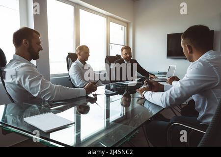 Eine Gruppe von Mitarbeitern des Unternehmens sitzt an einem Tisch in einem Besprechungsraum. Ein Team junger Geschäftsleute, die in einem Büro zusammenarbeiten und miteinander kommunizieren. Unternehmen Stockfoto