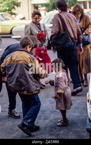 Zwei Jungen geben Münzen an ein Zigeunerkind, das auf der Straße bettelt, Moskau, Mai 1990 Stockfoto
