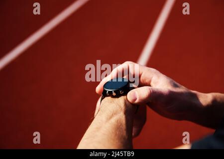 Nach den Übungen am Stadionständer überprüft der Mann die Uhr Stockfoto