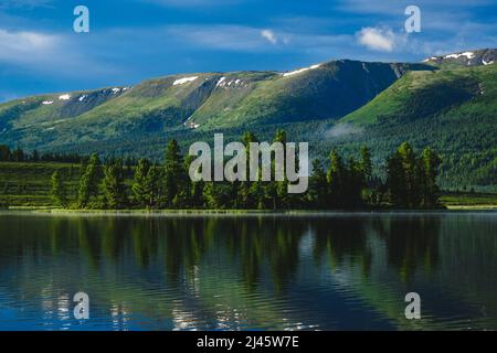 Der Wald spiegelt sich in den Gewässern eines Bergsees im Ulaganski-Bezirk der Altai-republik, Russland Stockfoto