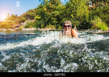 Das Mädchen liegt in einem Bach aus Bergwasser. Stockfoto