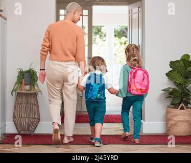 Waren bereit für den Tag. Aufnahme einer Frau, die mit ihren beiden Kindern das Haus verlässt. Stockfoto