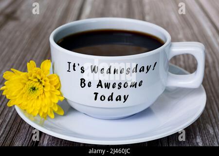 Text auf weißer Kaffeetasse mit gelber Blume auf Holzschreibtisch - Es ist Mittwoch, sei heute genial. Stockfoto
